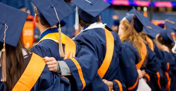 Graduates with their arms around each other at Commencement