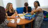A marriage and family therapy student works with a family seated around a table at the Couple and Family Therapy Center.