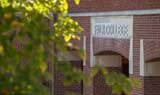 Falk College building exterior through the trees on a sunny day.