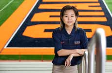 Ruby Liu stands in the stadium with the football end zone in the background.