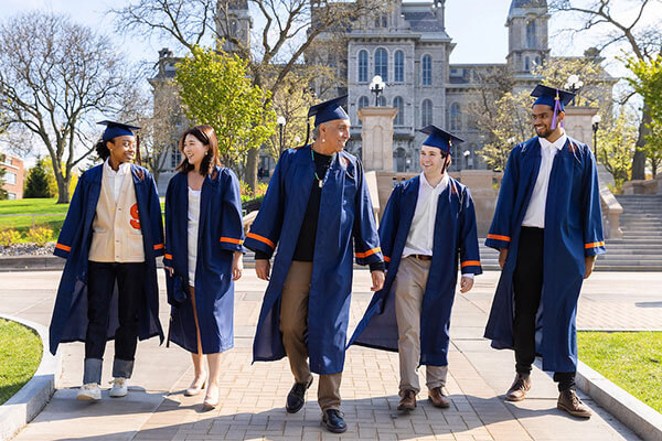 Class of 2023 graduates walk on main campus in front of the Hall of Languages.