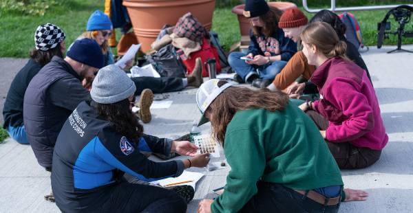 Students in circle on ground at Pete's Giving Garden