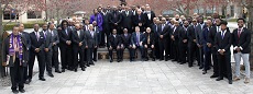 Group of Omega Psi Alumni on the orange grove in front of their organization plaque