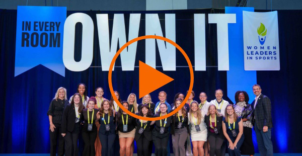 Falk students, staff, and faculty alongside representatives from Women Leaders in Sports on stage at the WLS convention.
