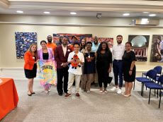 Students and staff standing and holding Syracuse multi colored tshirt