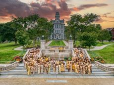 Women in gold gowns in front of Hall of Languages