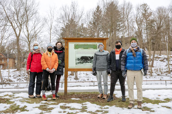 Students and faculty stand in front of Elmwood Park welcome sign.