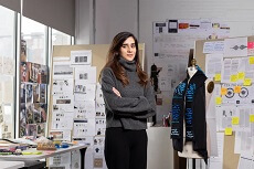 Rabia Razzaq stands next to the prototype of a weighted sensory scarf